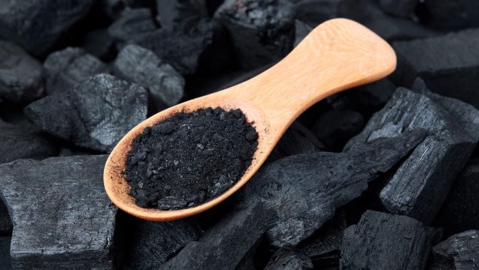 Black particles charcoal on a wooden spoon